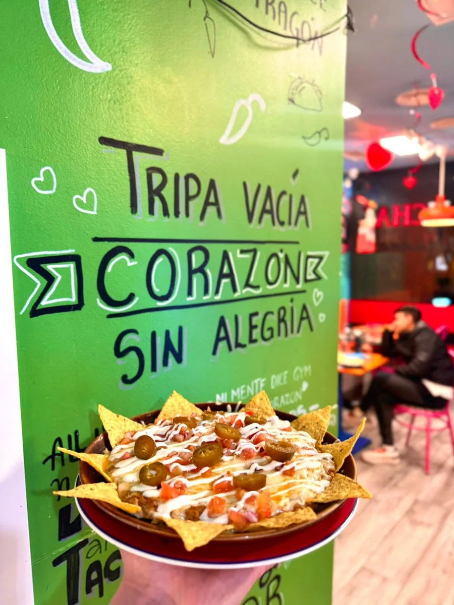 Nachos mexicanos en La Revancha junto a una pared decorada con una frase